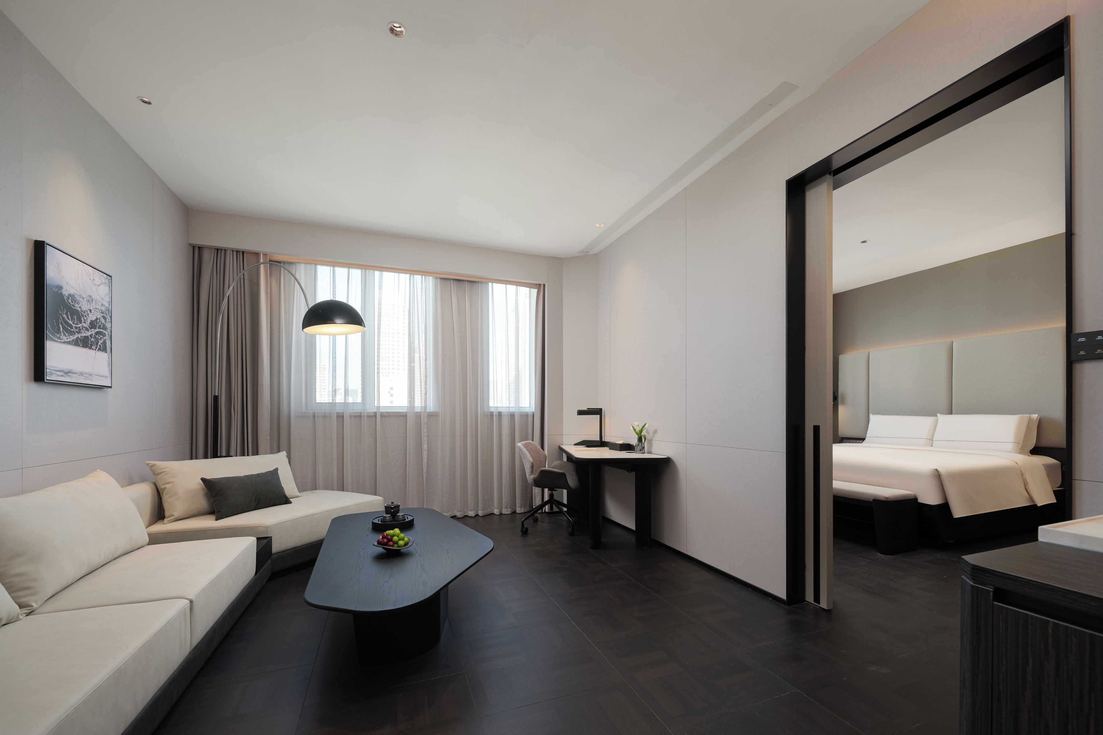 Et moderne hotelværelse med sofa, sofabord, skrivebord og seng.