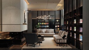 A modern living room with a sofa, armchairs, a coffee table, and a bookshelf filled with books. - Atour Hotel Dalian Xinghai Gaorji Road (Dalian)