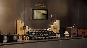 A breakfast bar with a variety of dishes and utensils, a wall-mounted television, and a wooden textured wall.