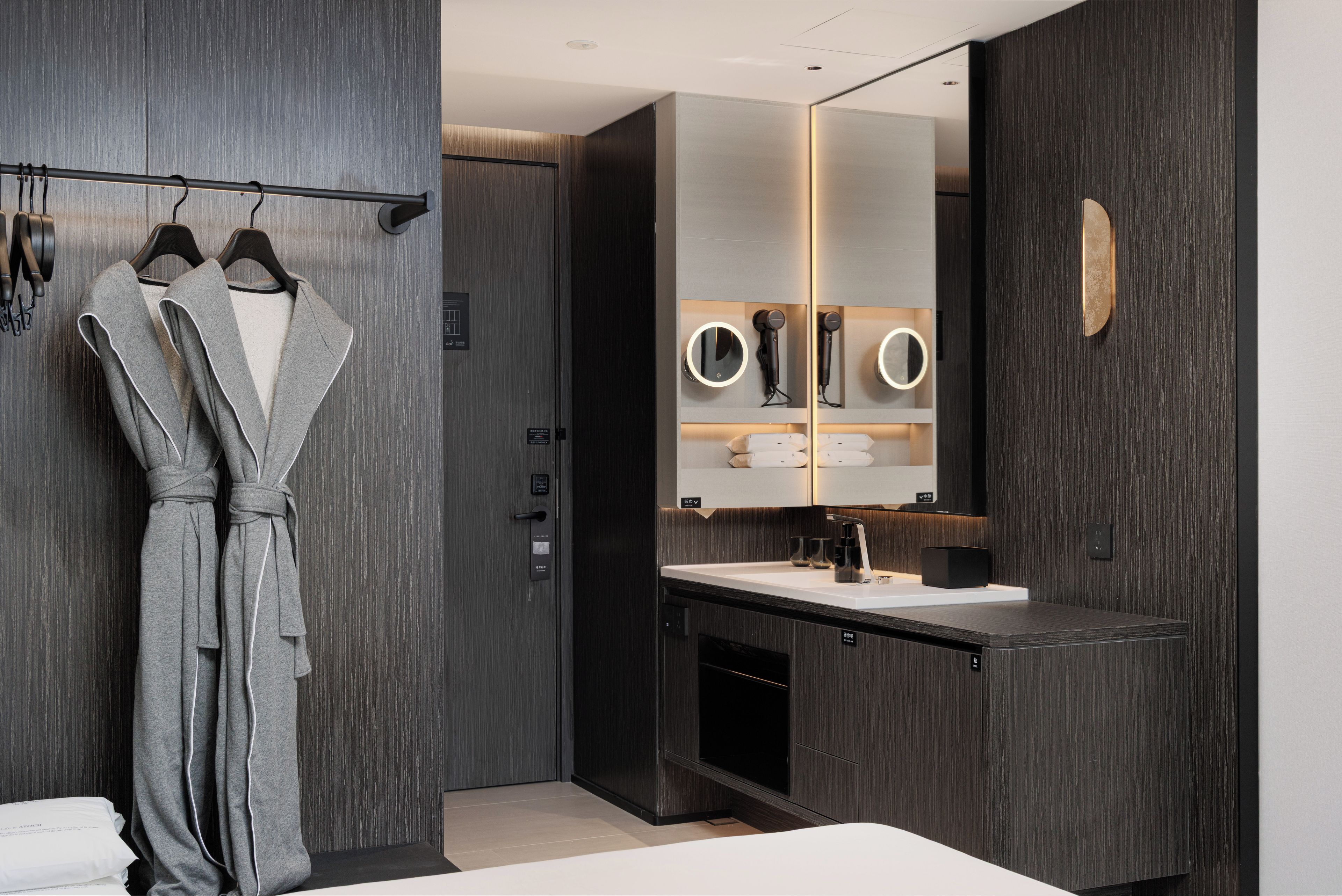 Une salle de bain moderne avec un grand miroir, un peignoir suspendu à un porte-manteau et un meuble-lavabo.