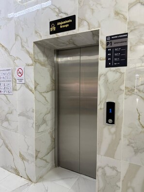 An elevator with a digital display, a sign indicating 'Alojamiento Orange,' and a directory for 'MAXIMO 4 PERSONAS' with apartment numbers. - Cathedral Centro Histórico D4 (Guadalajara)