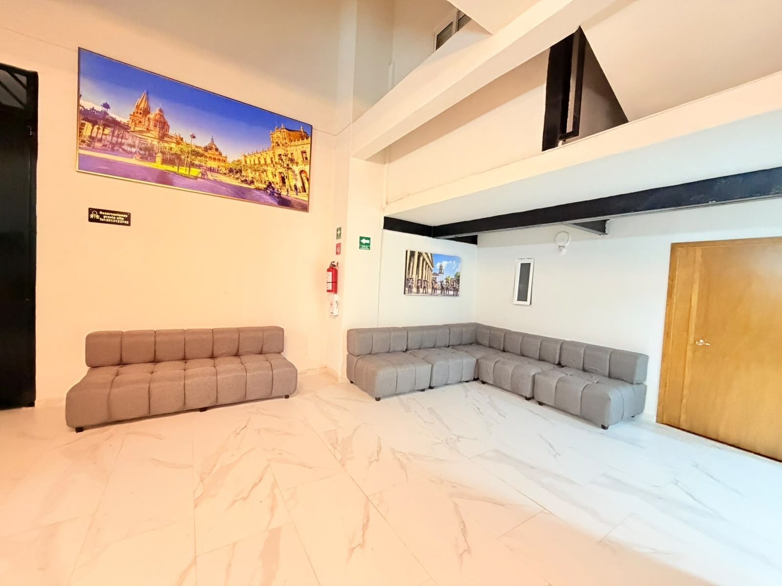 A hotel lobby with a reception desk, a large seating area with sofas, and a large wall mural.