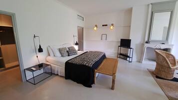 A modern bedroom with a bed, bedside tables, a chair, a television, and a fireplace.