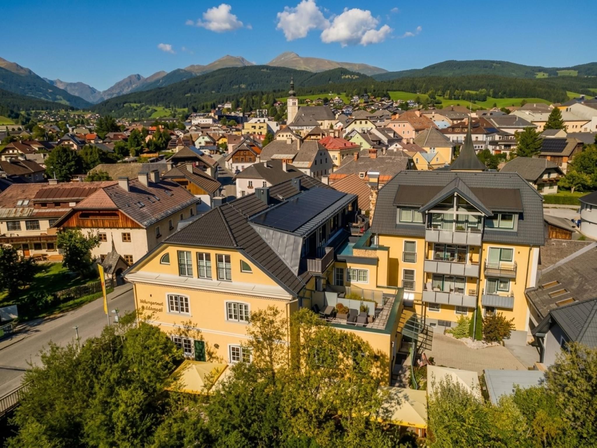 Un quartier résidentiel avec des maisons, une église et des montagnes en arrière-plan.