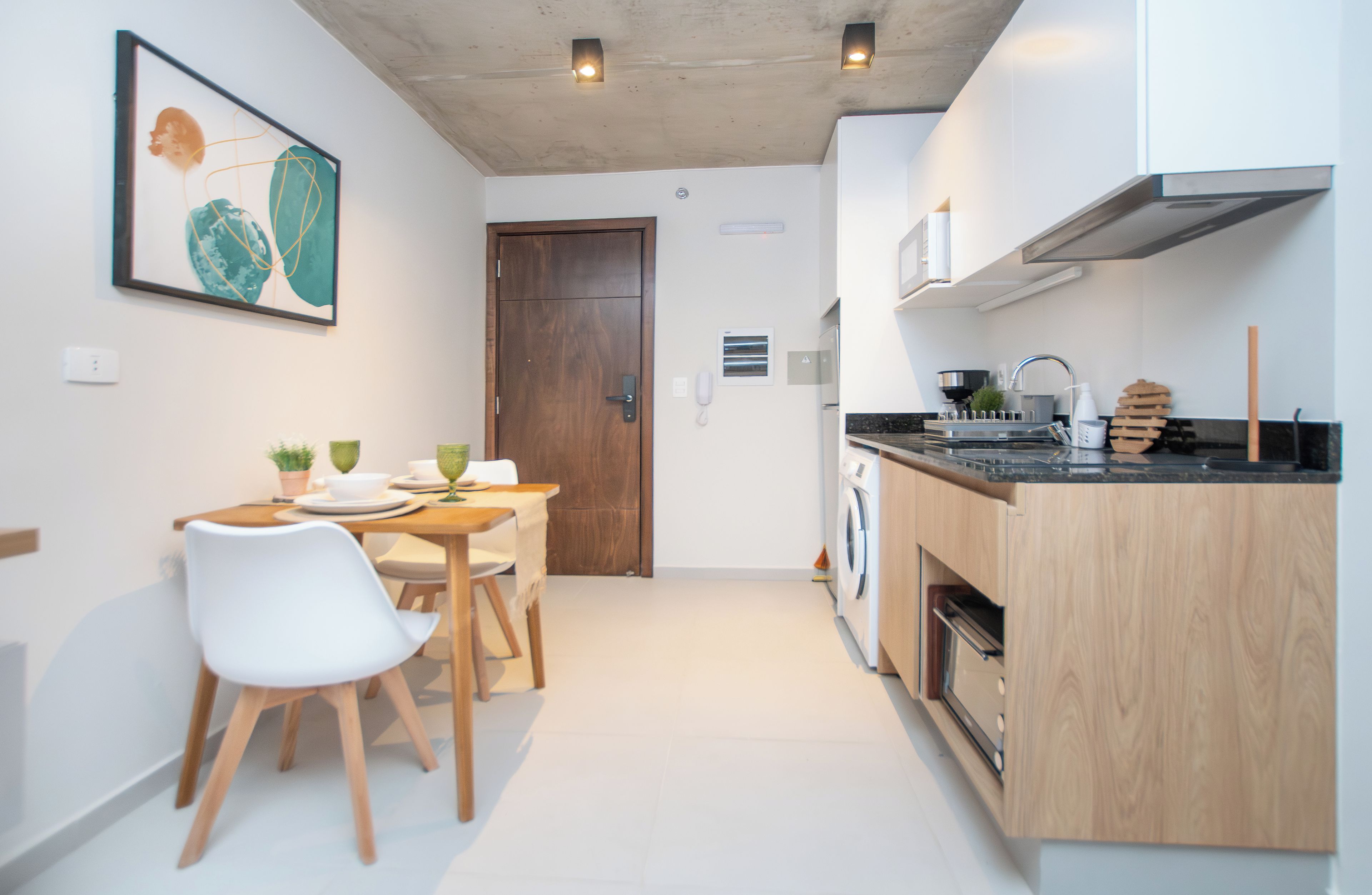 Cocina moderna con comedor, que incluye una mesa de madera, sillas y un cuadro en la pared.