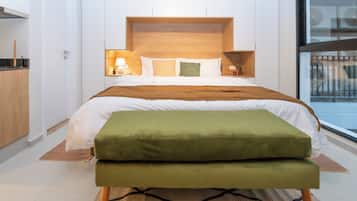 A modern bedroom with a large bed, a wooden headboard, bedside tables with lamps, and a view of the outside through a window.