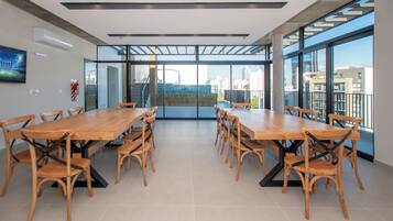 Un salón de conferencias con una larga mesa y sillas, ventanas grandes y vistas a la ciudad.