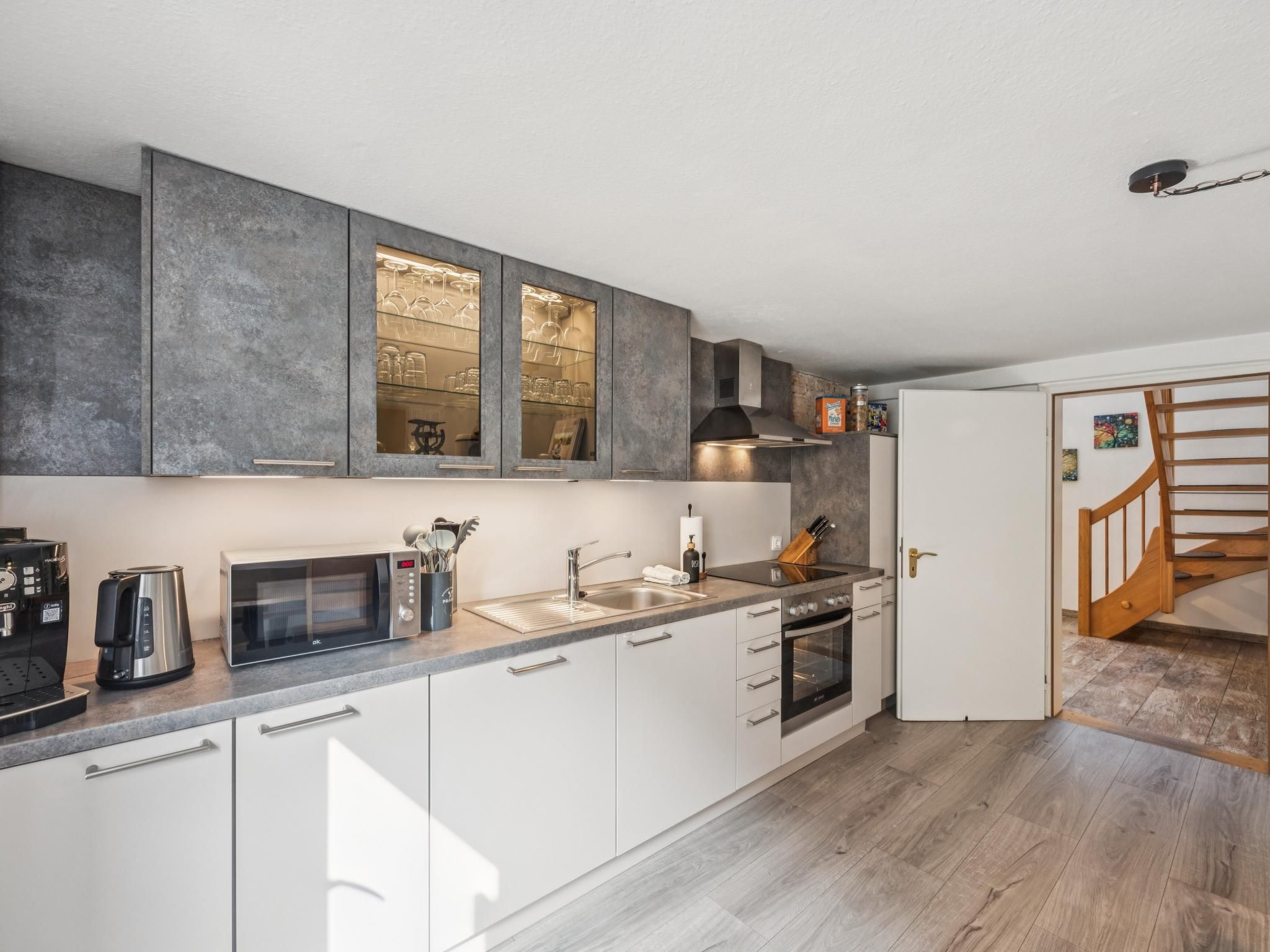 A modern kitchen with a built-in microwave, coffee maker, and a stainless steel sink.