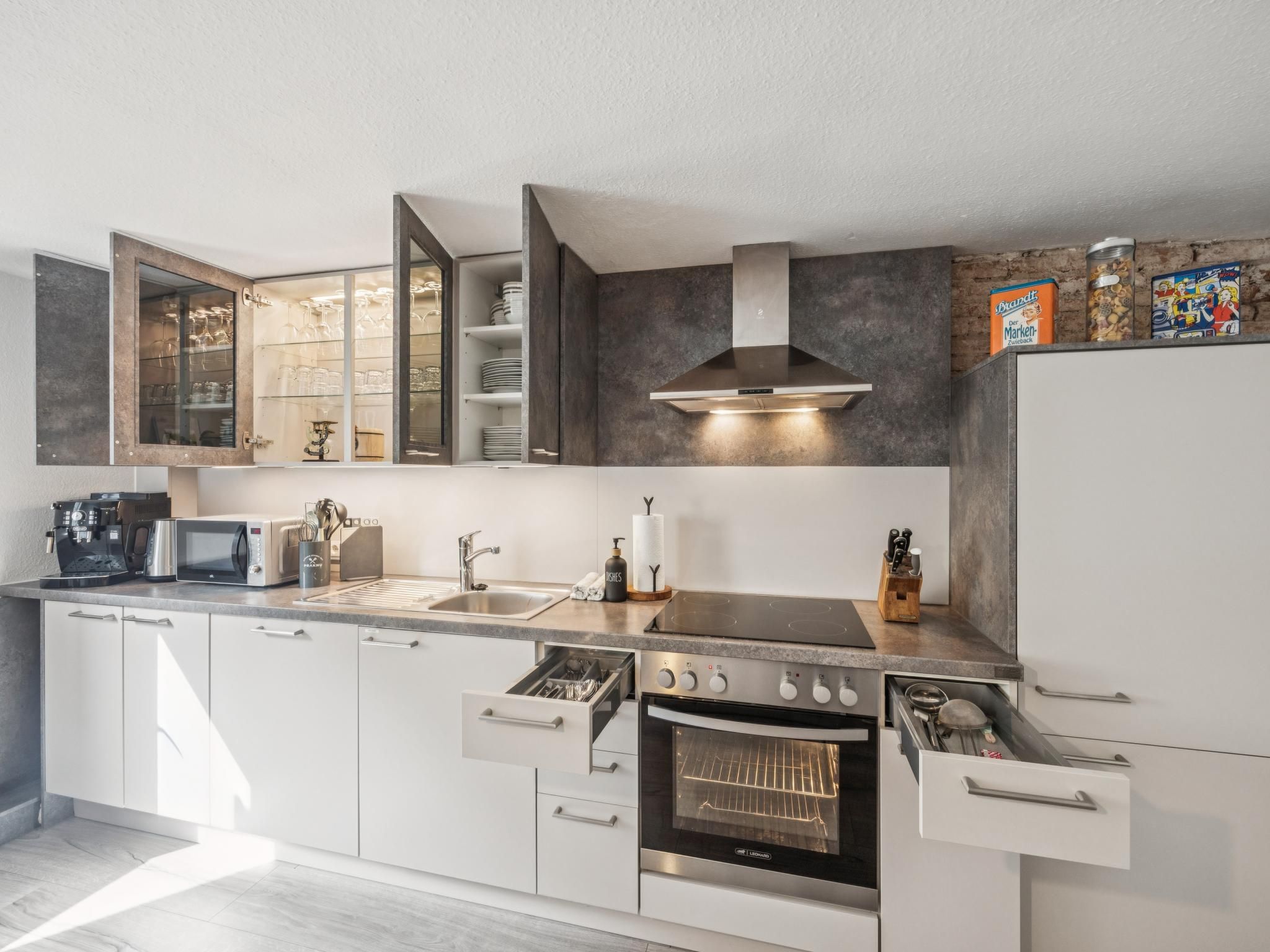 A modern kitchen with a built-in oven, a microwave, and a coffee machine.