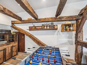 A room with a foosball table, shelves with bottles, and a vintage radio.