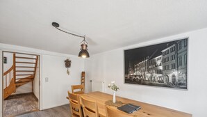 A dining area with a wooden table, chairs, a pendant light, a radiator, and a black and white photograph on the wall. - Modern group house in the center of Herbolzheim (Herbolzheim)