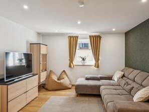 A modern living room with a flat-screen TV, a sofa, a coffee table, and a cabinet.
