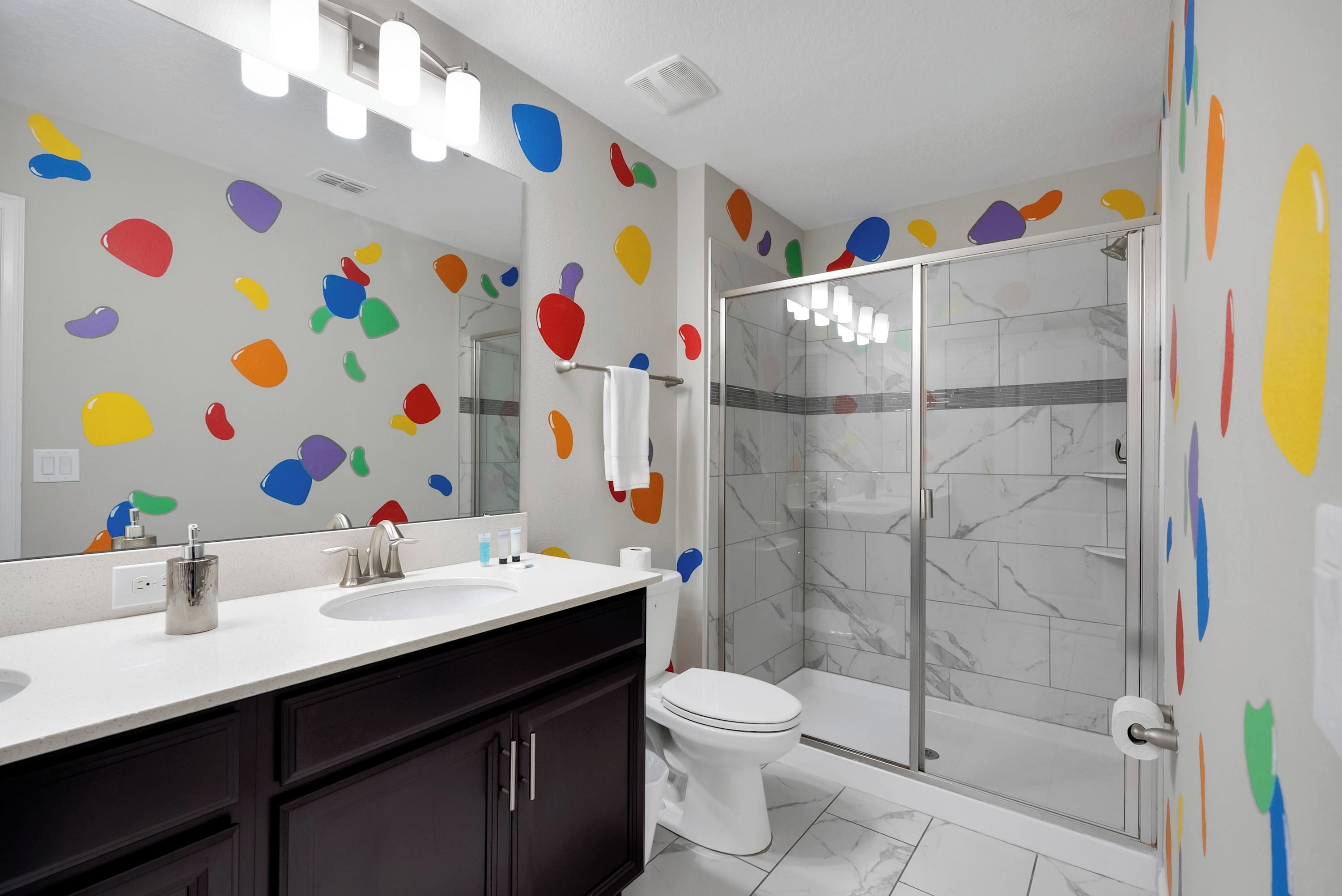 Une salle de bain moderne avec une douche à parois de verre, des toilettes blanches et un meuble-lavabo avec un miroir.