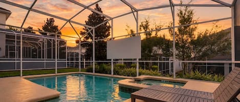 A covered outdoor swimming pool with lounge chairs and a view of the sunset.