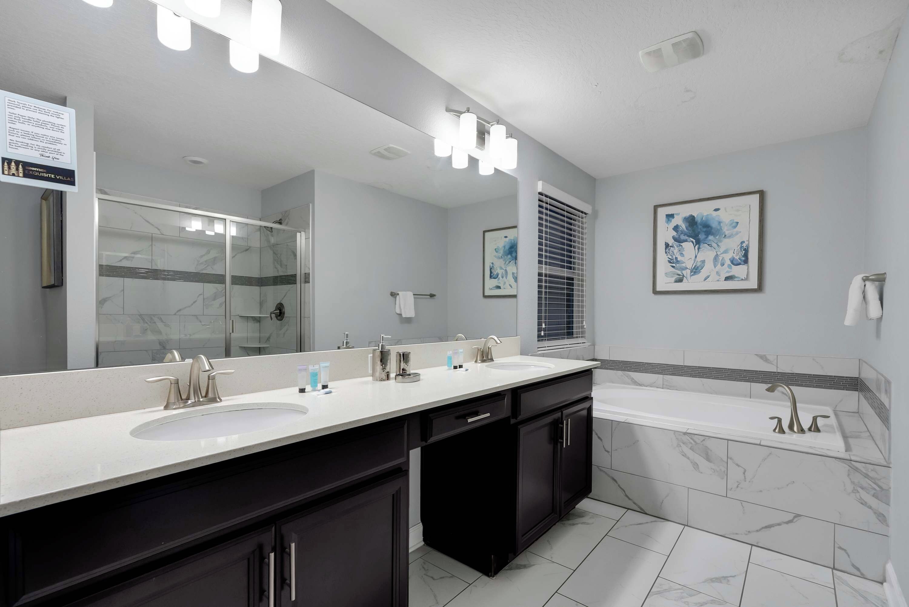 Un baño moderno con un espejo grande, lavamanos dobles y una bañera.
