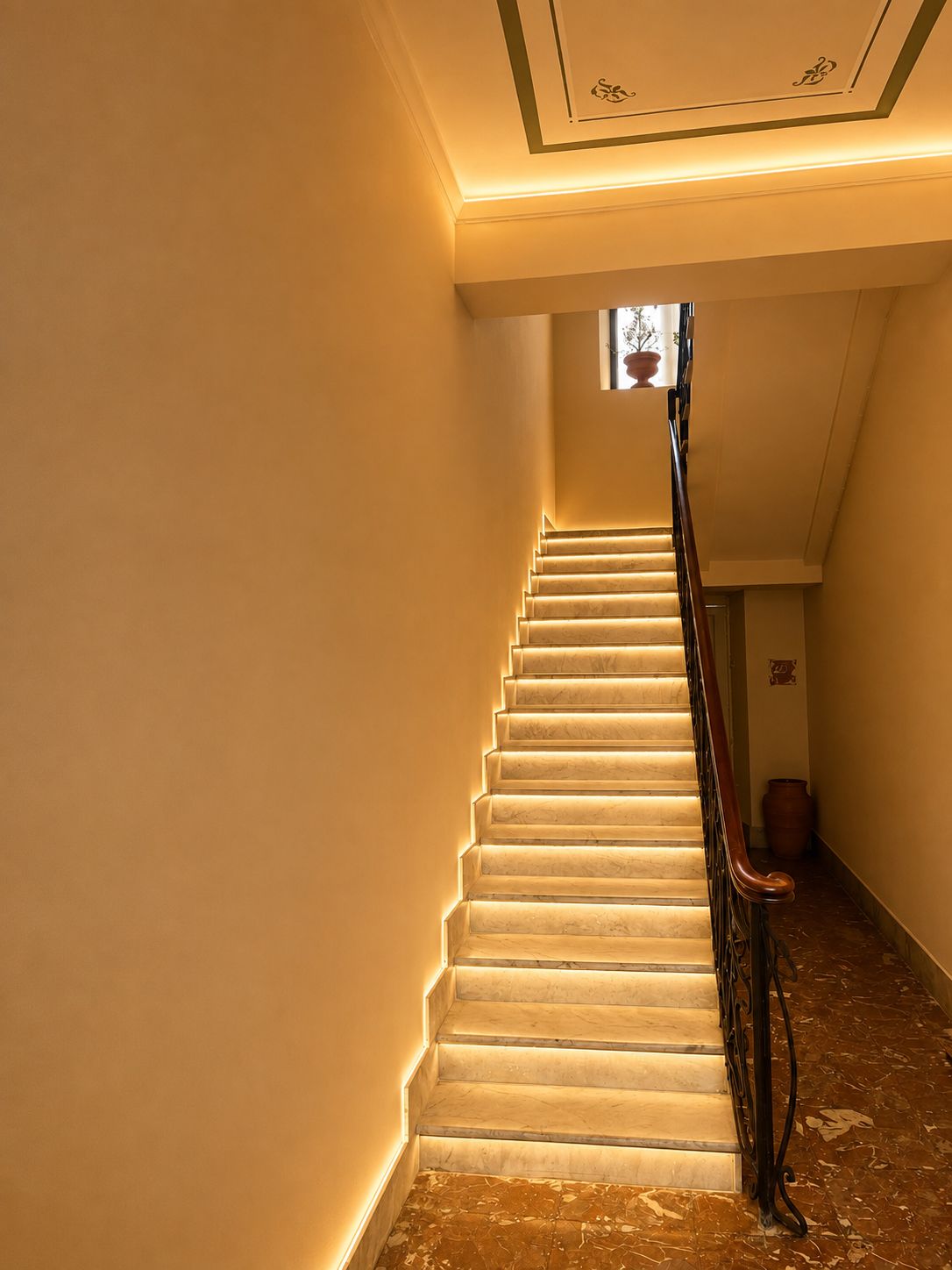 A staircase with a handrail and a small window at the top.