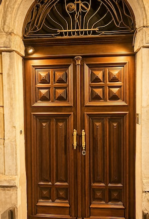 A double wooden door with intricate carvings and a metal handle.