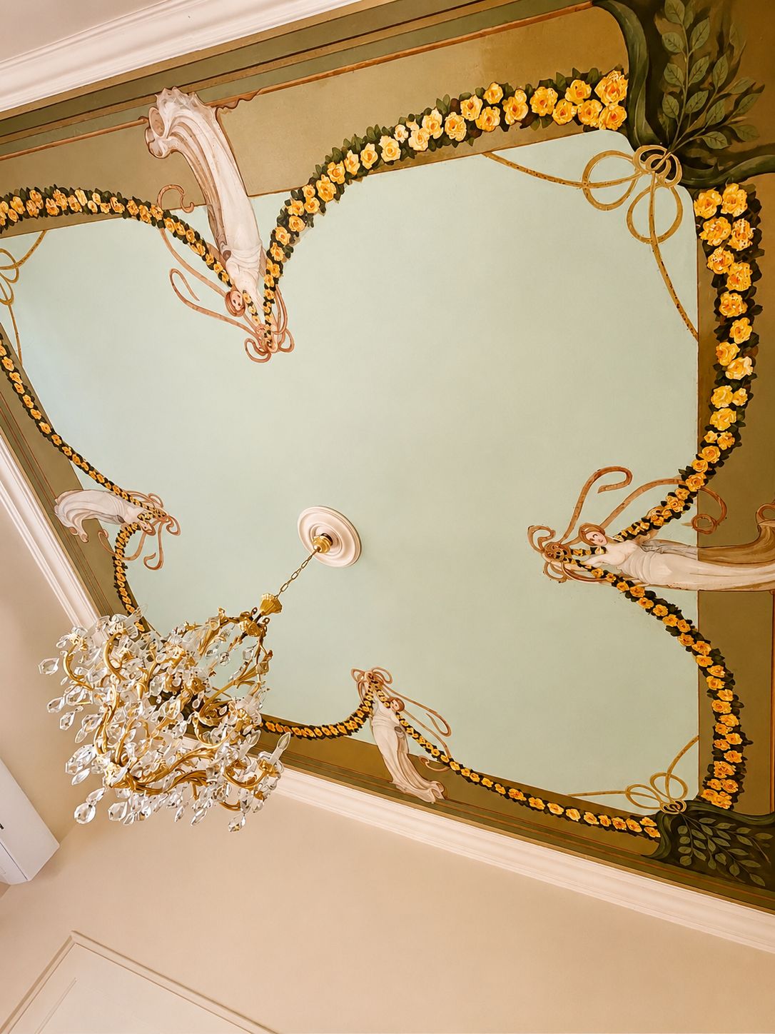 Un plafond orné de motifs dorés et noirs, comprenant des motifs floraux et un lustre.