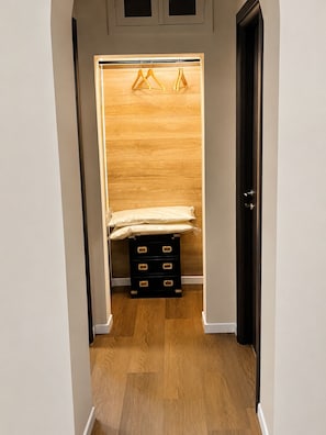 A walk-in closet with a wooden wardrobe, a bed, and a black storage unit.