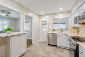 A modern kitchen with white cabinetry, a dishwasher, and a stove. - 8 Bells Bungalow - Cozy, Stylish, Prime Location (Annapolis)