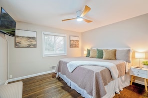 A bedroom with a bed, a ceiling fan, a TV, and framed artwork on the wall. - 8 Bells Bungalow - Cozy, Stylish, Prime Location (Annapolis)