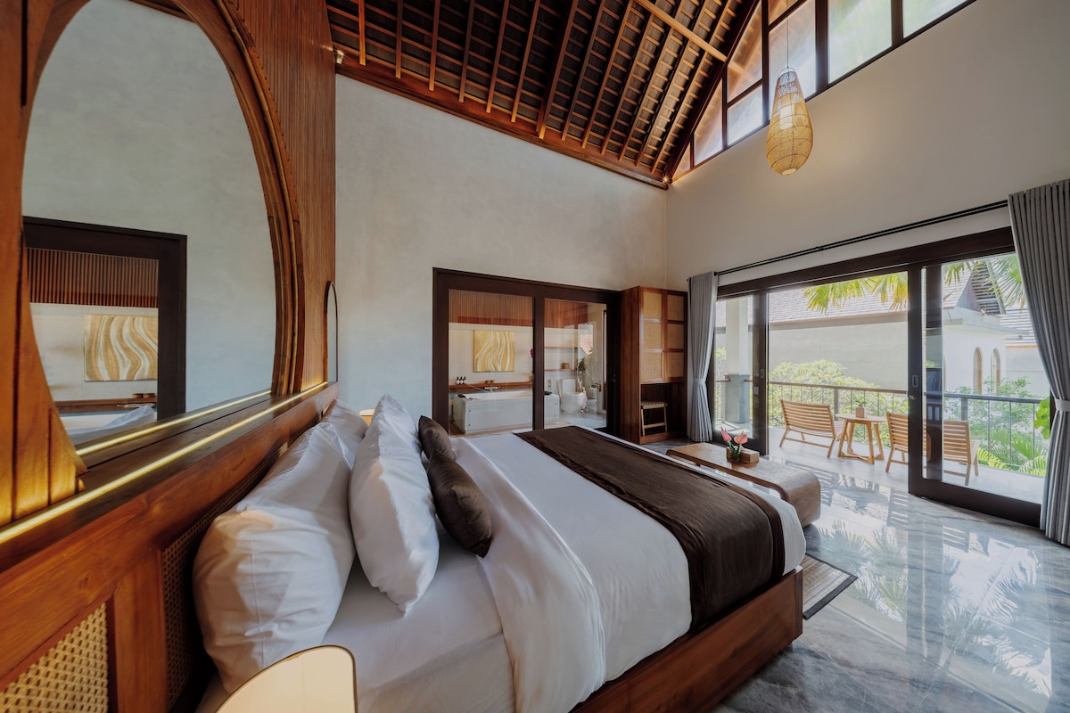 A modern hotel room with a large bed, a balcony with a view, and a large mirror.