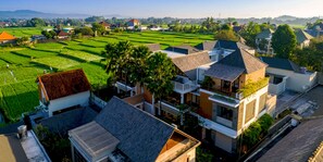 A residential area with modern houses, a visible water tank, and lush green fields in the background. - Andara Hide Ubud villa (Gianyar)