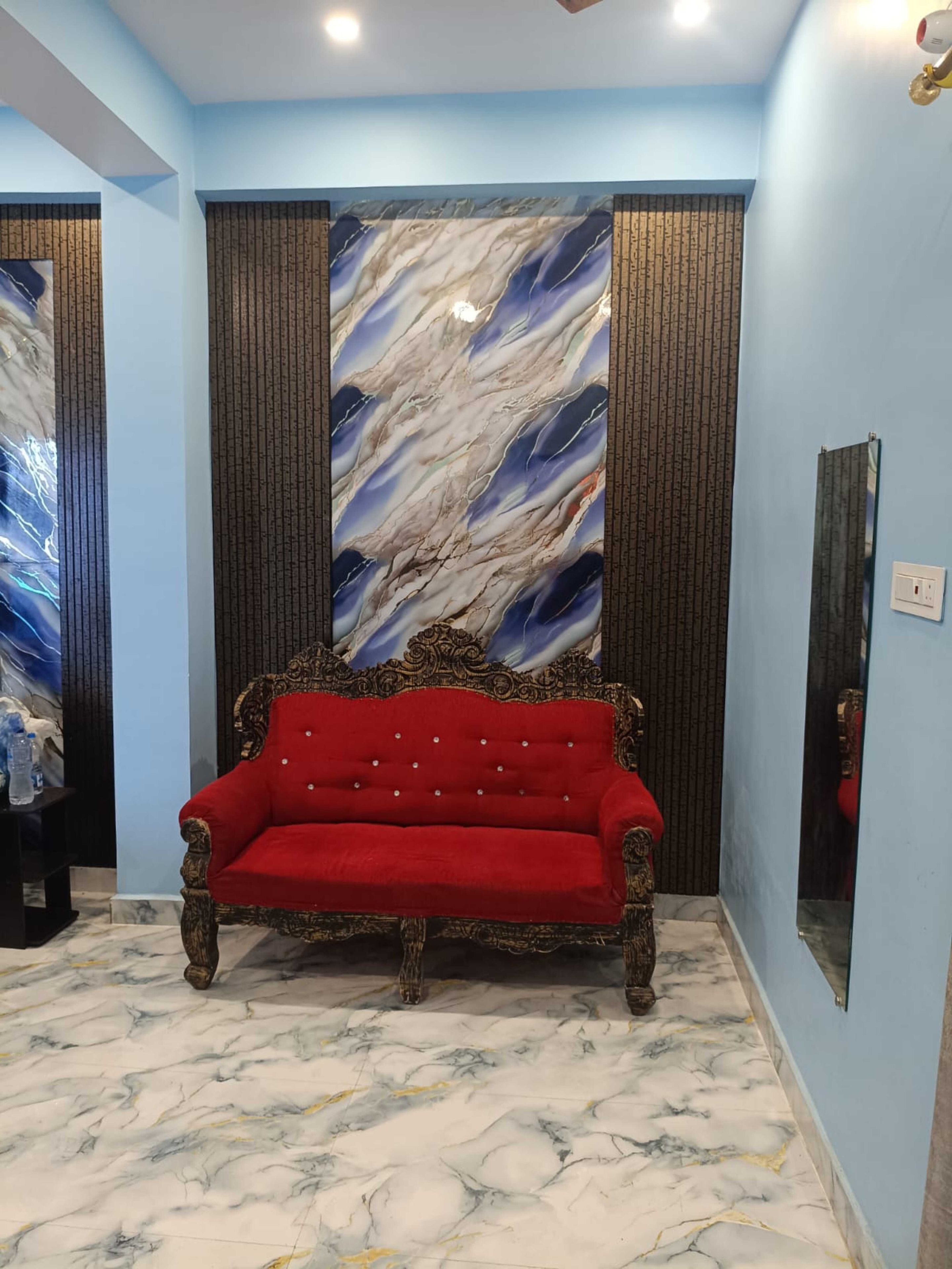 Una habitación con un sofá tapizado rojo, piso con diseño de mármol y un panel decorativo con apariencia de mármol.