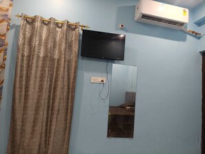 Habitación con televisión de pantalla plana montada en la pared, un enchufe y un equipo de aire acondicionado.