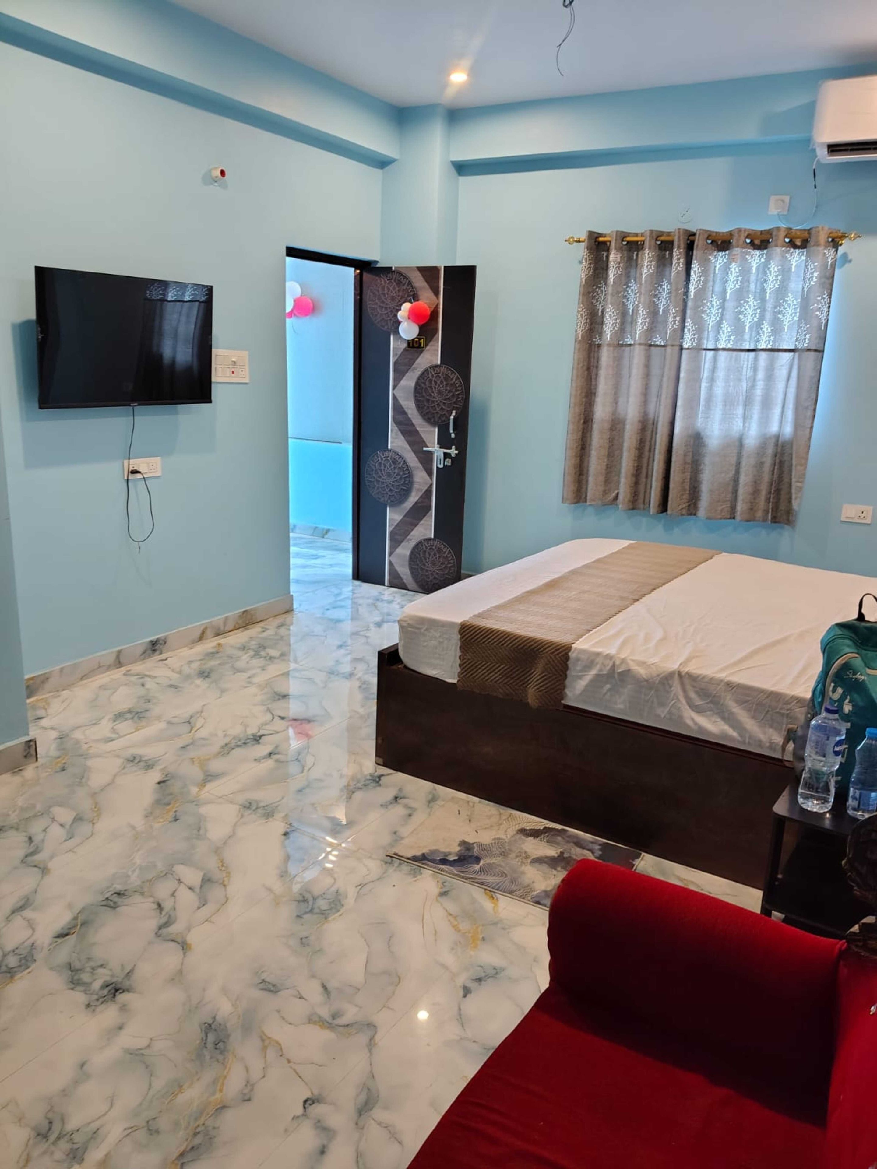 Una habitación de hotel con una cama, un televisor, una puerta de baño y un sofá rojo.