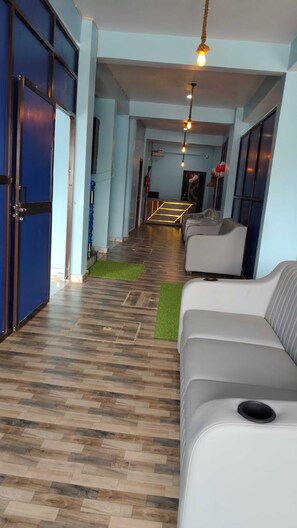 Un pasillo de hotel con suelo de madera, un sofá y una puerta.