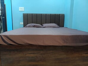 Una cama con cabecera, un edredón marrón y dos almohadas.