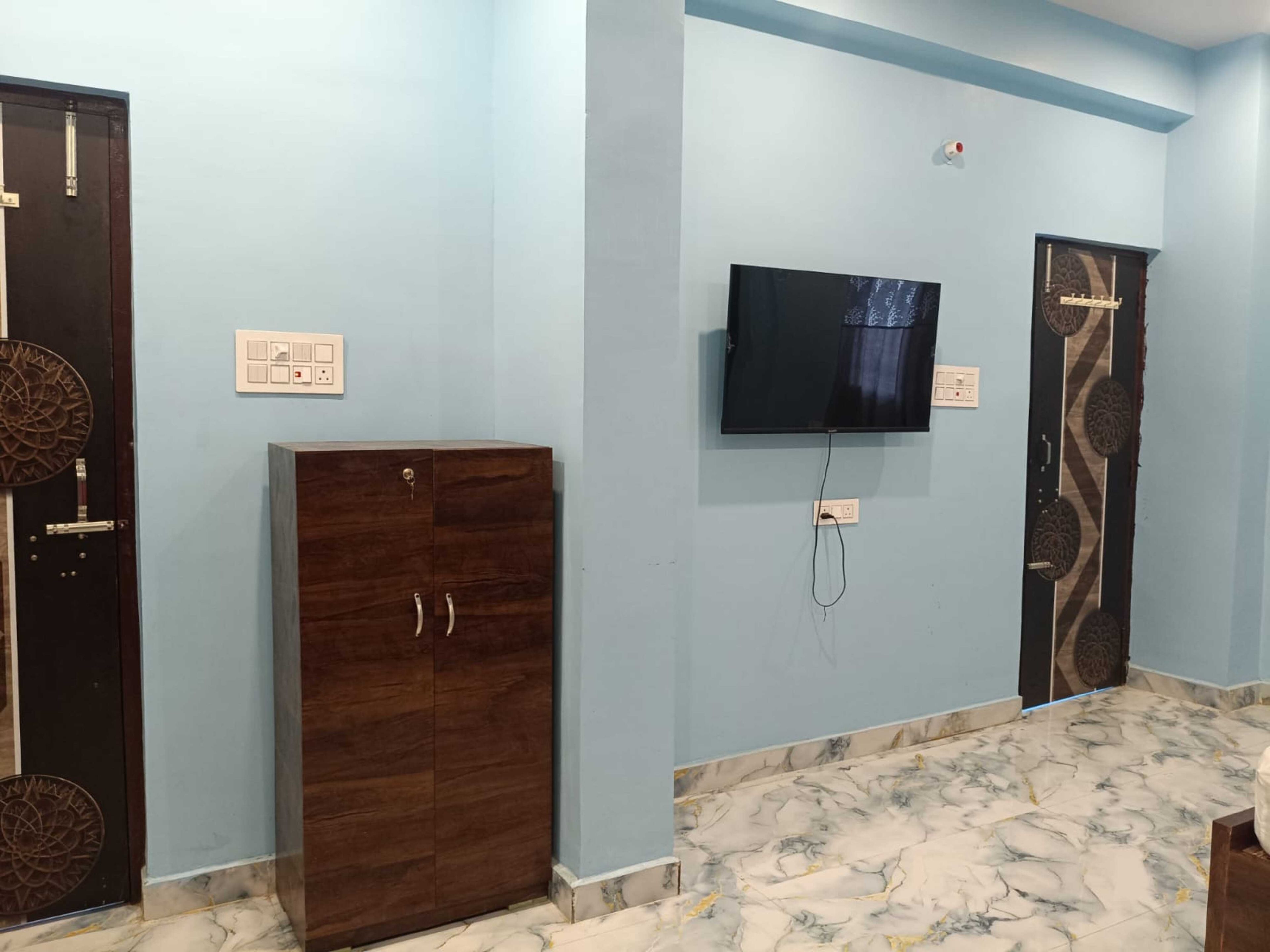 Una habitación con suelo de mármol, un televisor montado en la pared y dos puertas con diseños decorativos.