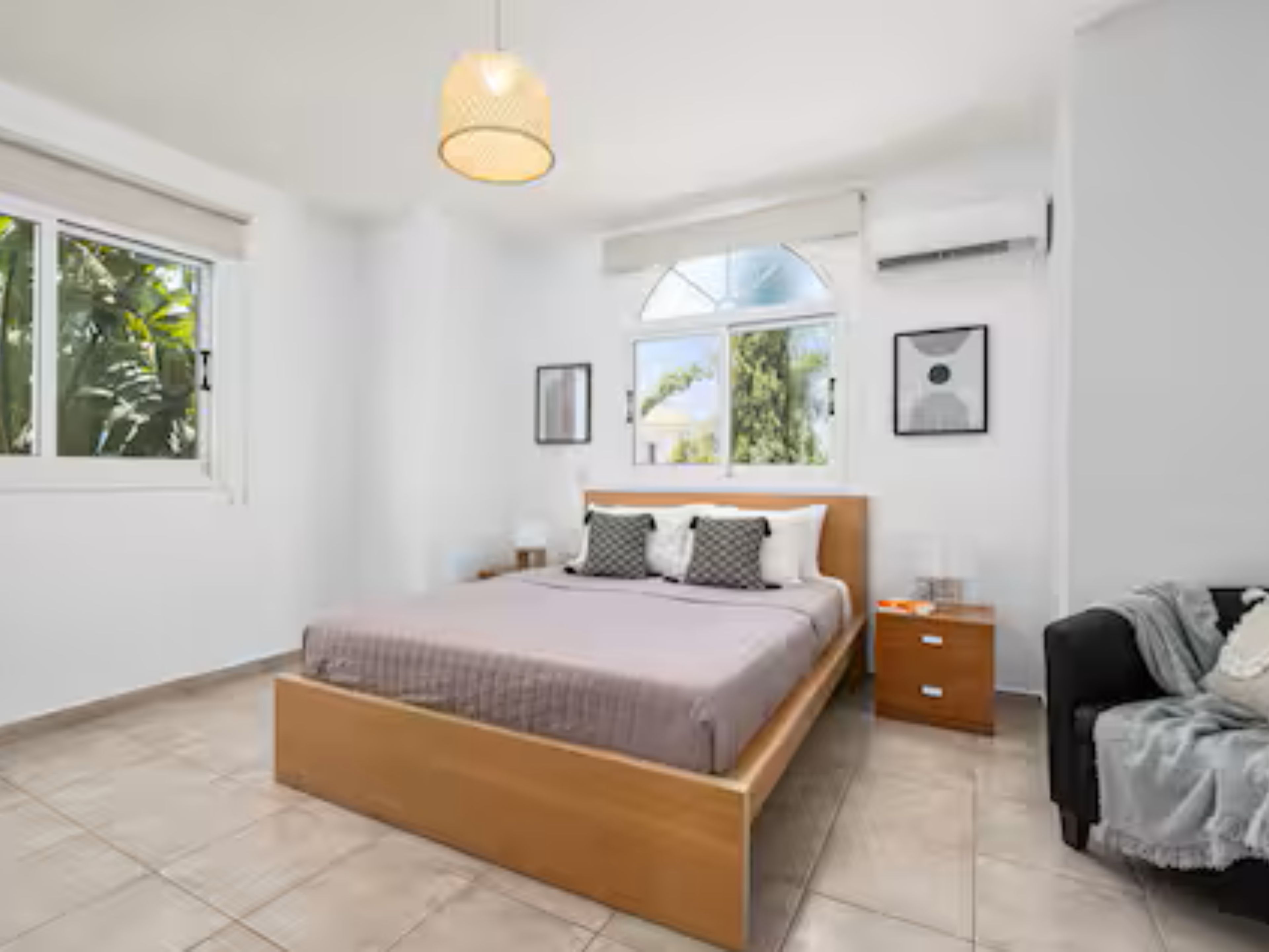 Ein Schlafzimmer mit einem Bett, einem Nachttisch, einem Sessel und einem Fenster.