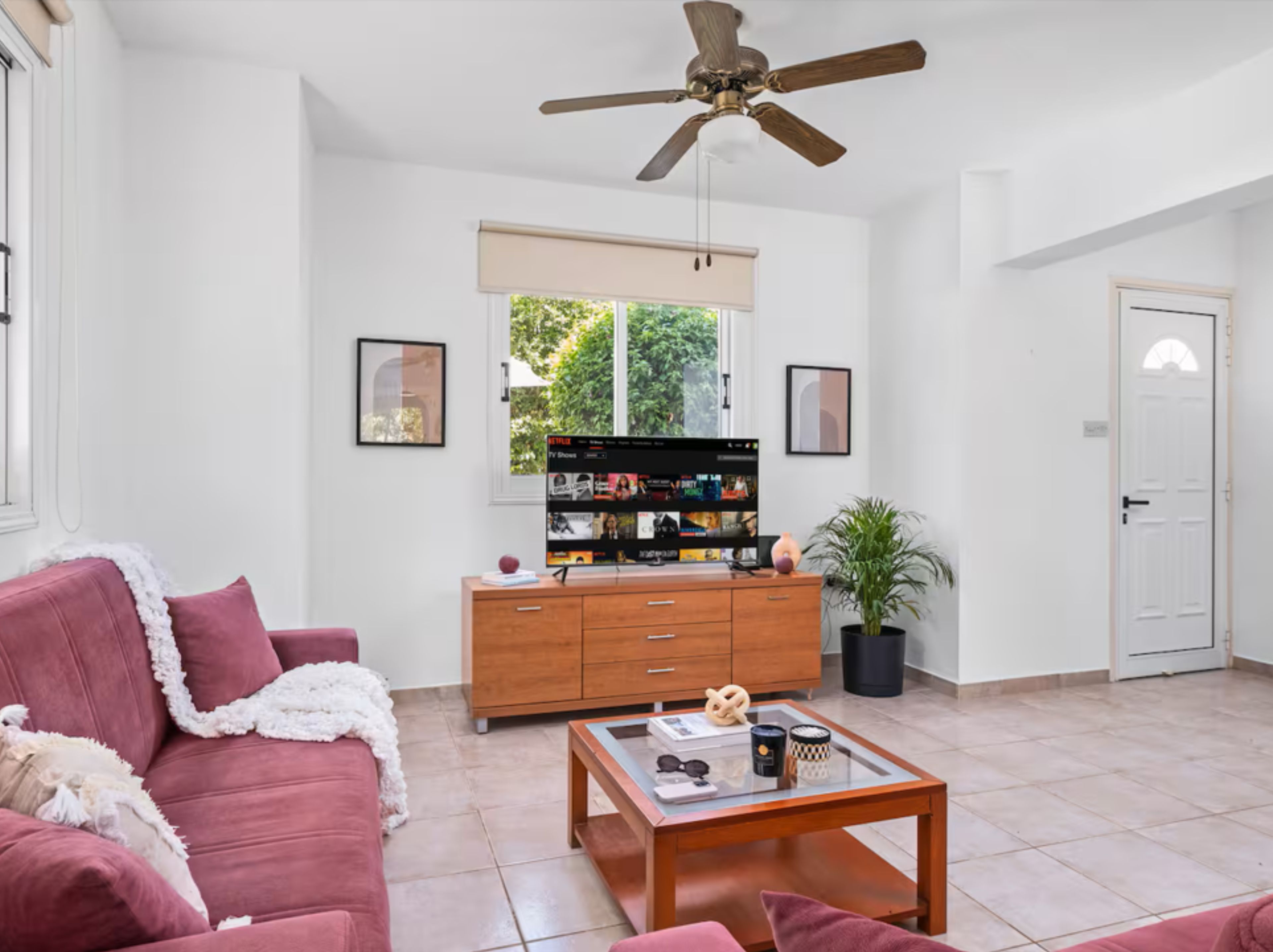 Una sala de estar con un sofá, una mesa de centro, televisor y un ventilador de techo.