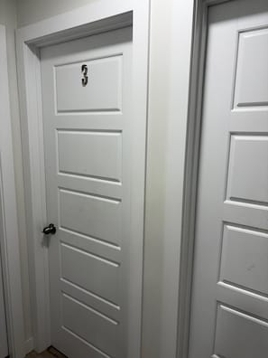 A white door with a numeric keypad lock and a doorbell.