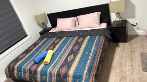 Ein Schlafzimmer mit einem Bett, zwei Nachttischen, einem Fenster und einem Beistelltisch.