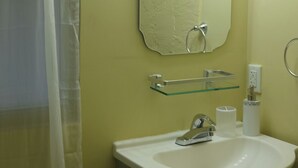 Een badkamer met een wit wastafel, spiegel en verlichte wastafelmeubel.