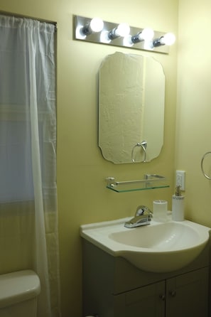 Une salle de bain avec un lavabo blanc, un miroir et une coiffeuse éclairée.