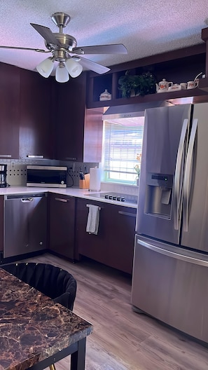 A modern kitchen with stainless steel appliances, a ceiling fan, and a window with blinds. - Iconic Wynwood Artsy Bungalow - Walk to Everywhere (Miami)