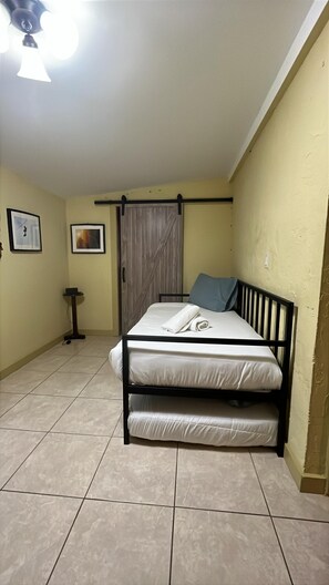 A room with a bed, a door, a small table, and a ceiling fan. - Iconic Wynwood Artsy Bungalow - Walk to Everywhere (Miami)