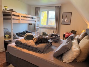 A bedroom with bunk beds, a window with curtains, a radiator, and a bedside table with a lamp. - Maison François: a vacation home for a carefree stay surrounded by nature near Bruges (Oostkamp)