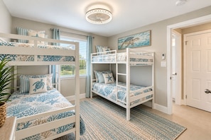 Ein Zimmer mit Etagenbetten, einer Deckenleuchte, einem Bild einer Meeresschildkröte und einer Tür.