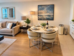 Ein modernes Wohnzimmer mit einer Couch, einem Esstisch für vier Personen und einem großen Gemälde an der Wand.