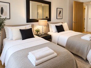 Ein Hotelzimmer mit zwei Betten, einem Nachttisch mit Lampe, einem Spiegel und einer Tür.