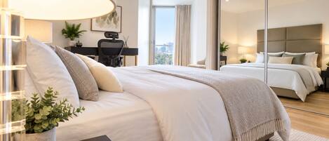 Une chambre moderne avec un grand lit, un bureau et une vue sur la ville grâce à une grande fenêtre.