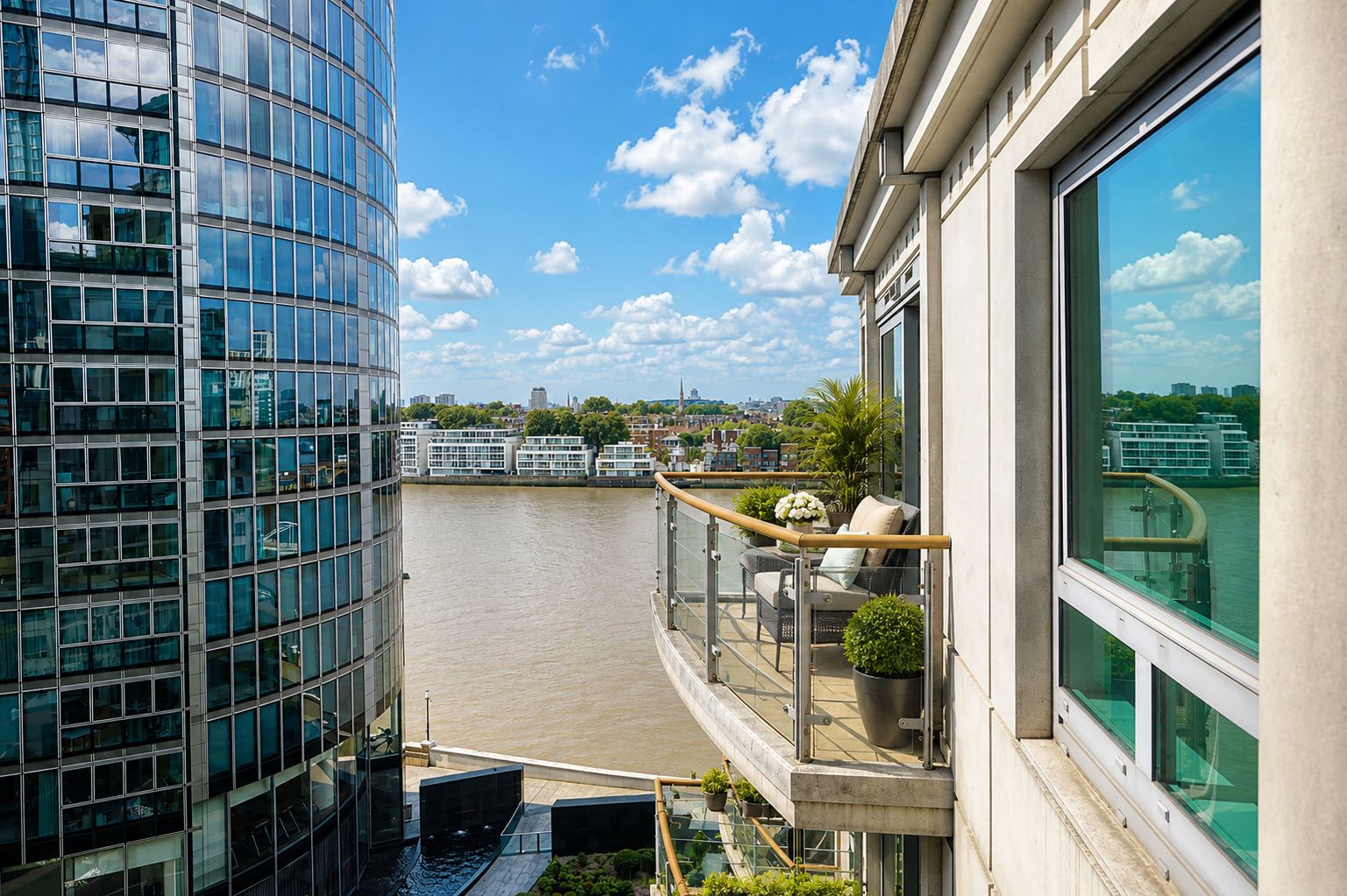 Un edificio moderno de gran altura con fachada de vidrio, vistas al río, un balcón con mobiliario exterior y cielo despejado.