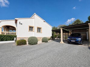 Ein zweistöckiges Gebäude mit überdachtem Parkbereich und einem blauen Auto darin.