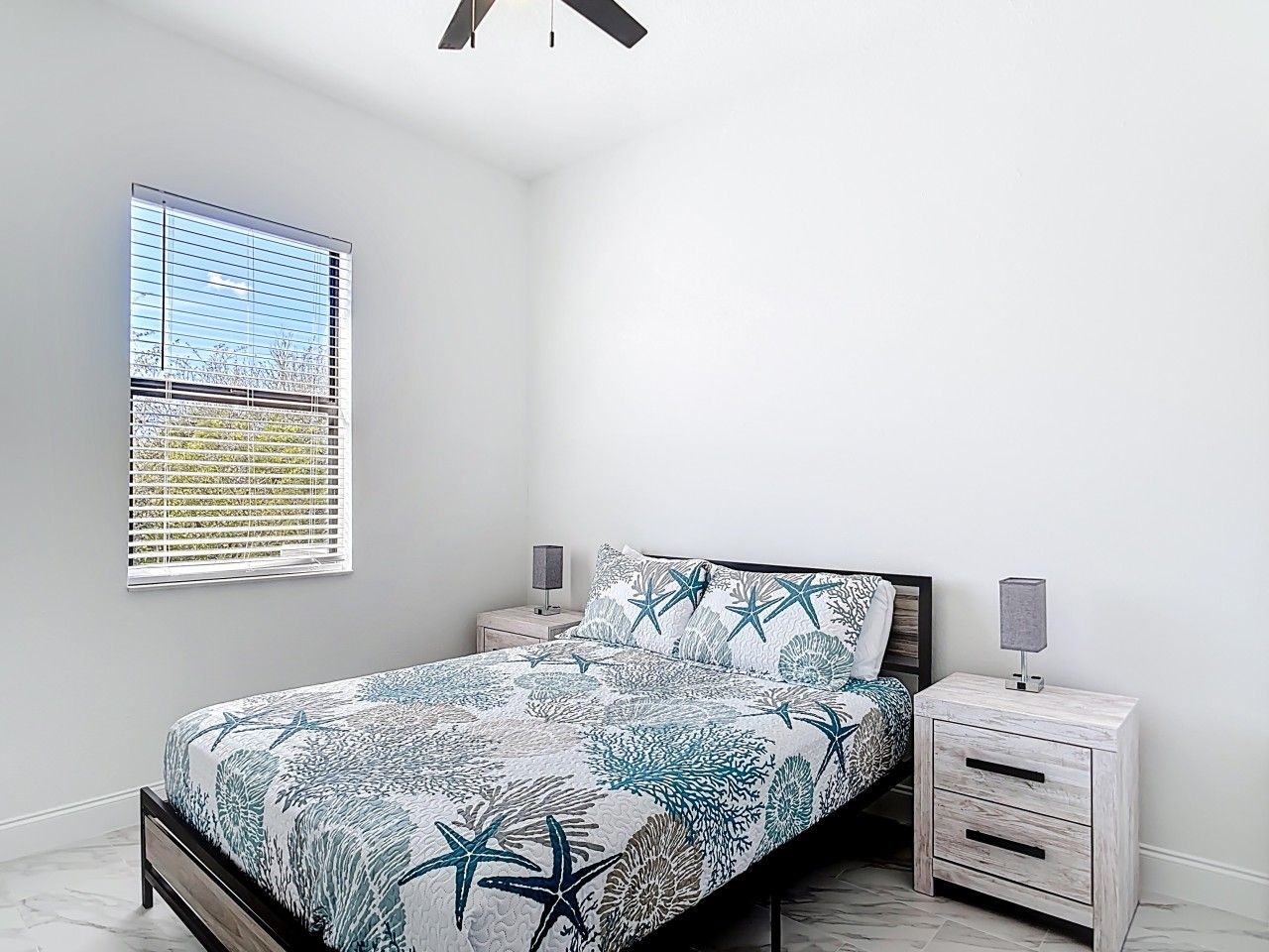 A bedroom with a bed, nightstands, a window, and a ceiling fan.