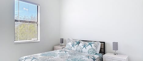 A bedroom with a bed, nightstands, a window, and a ceiling fan.